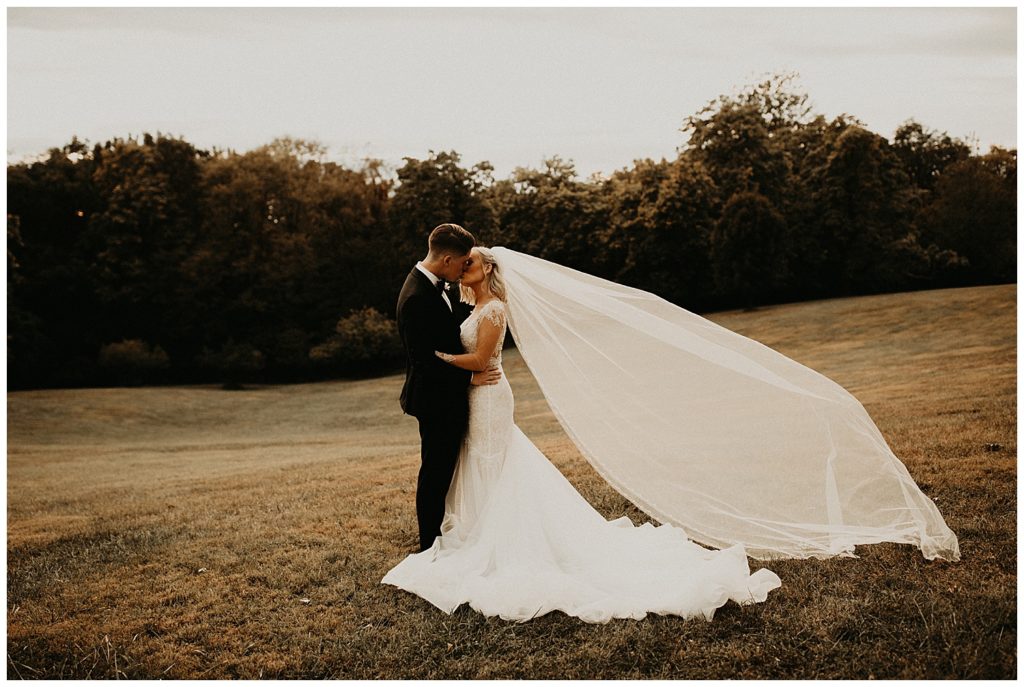 bride and groom taking wedding day portraits in meadow