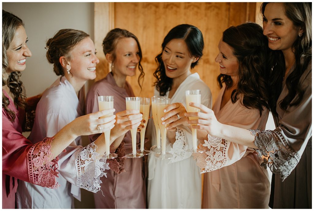 bride drinking mimosas with bridesmaids on wedding day