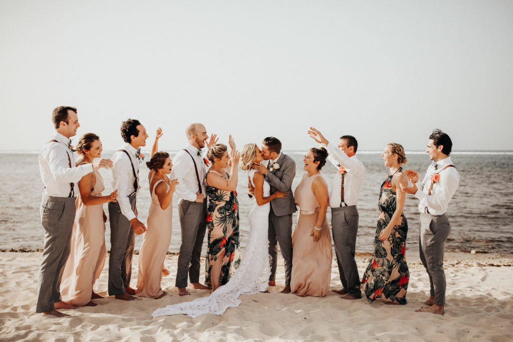 bride and groom with their wedding party on the beach