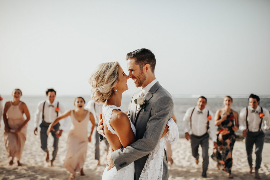 bride and groom with their wedding party on the beach