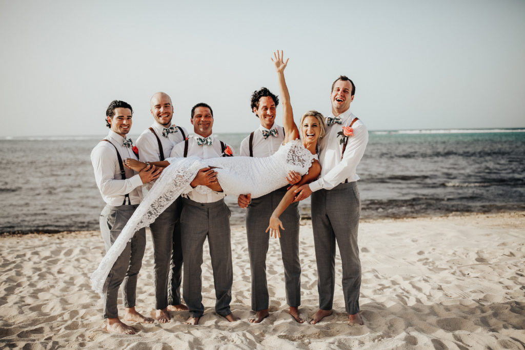 bride and groom with their wedding party on the beach