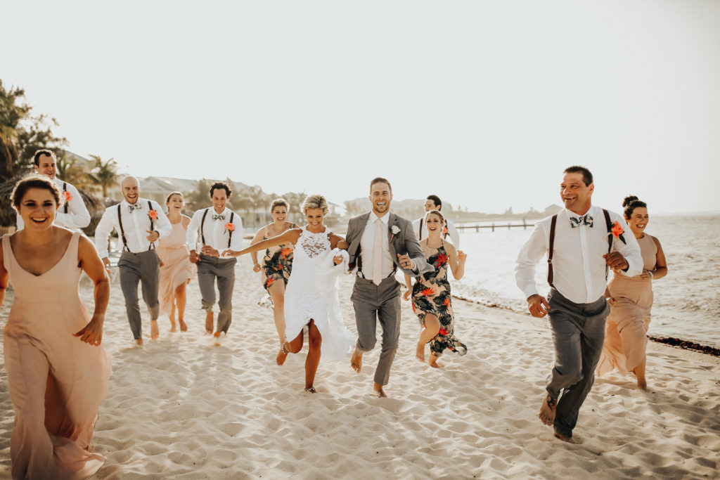 bride and groom with their wedding party on the beach
