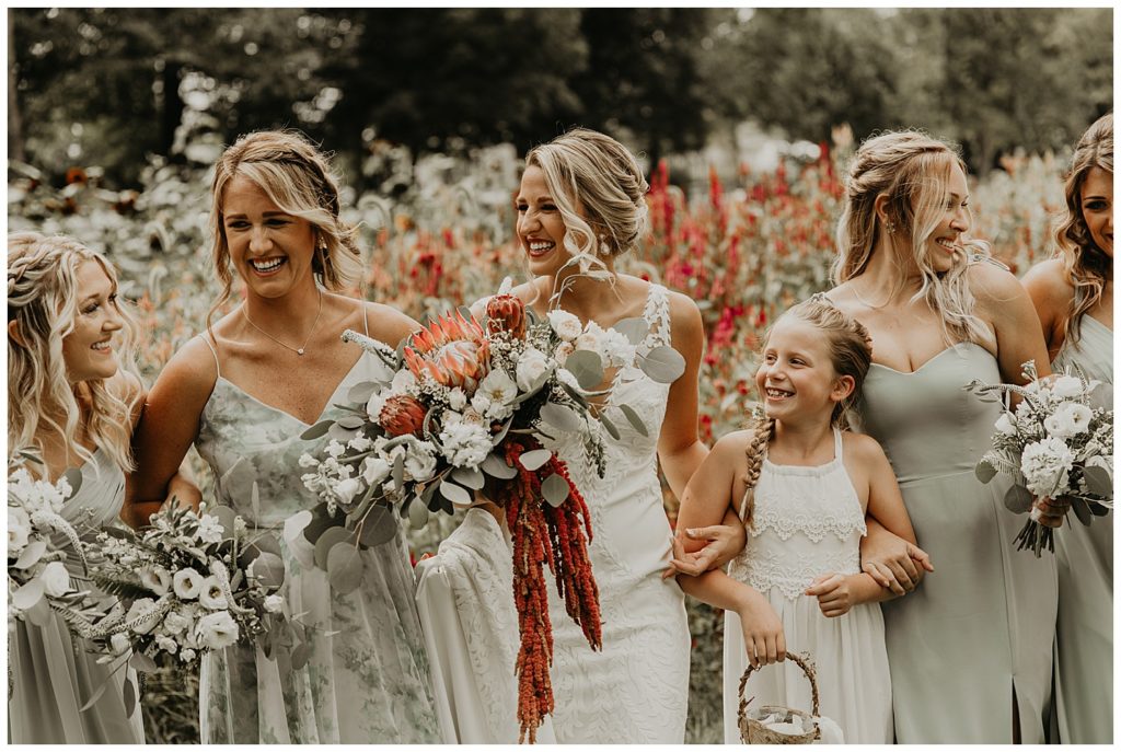 bride in boho lace wedding dress and blush bouquet with king protea and eucalyptus, bridesmaids in light grey dresses