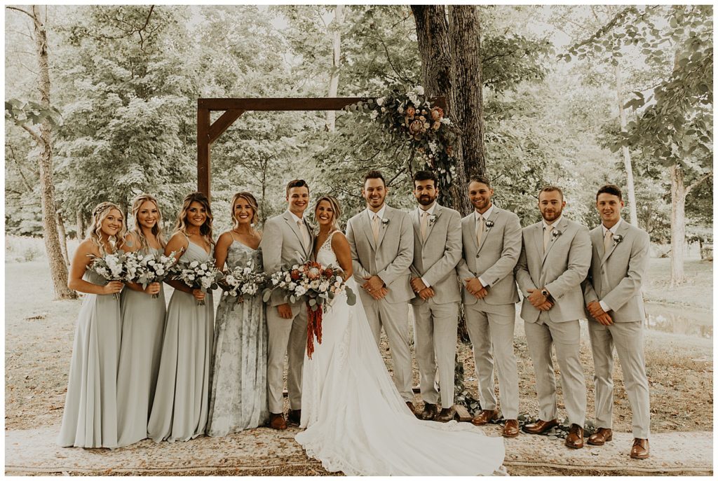 bridal party photo, bride in boho lace wedding dress and blush bouquet with king protea and eucalyptus, bridesmaids in light grey dresses