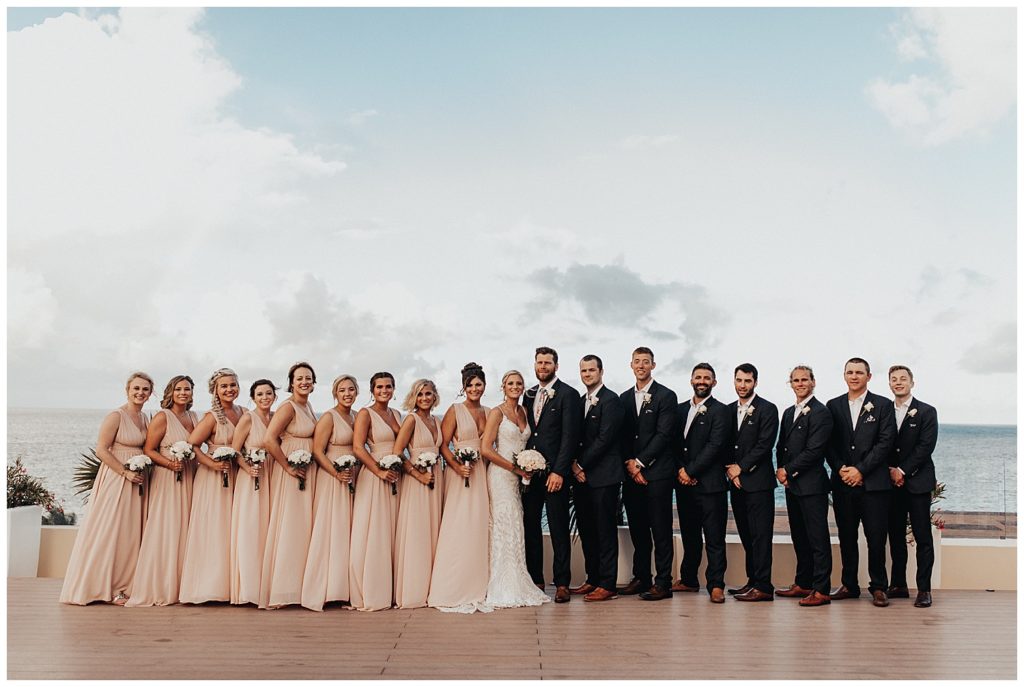 bridal party taking photos on the beach before wedding ceremony in cancun mexico