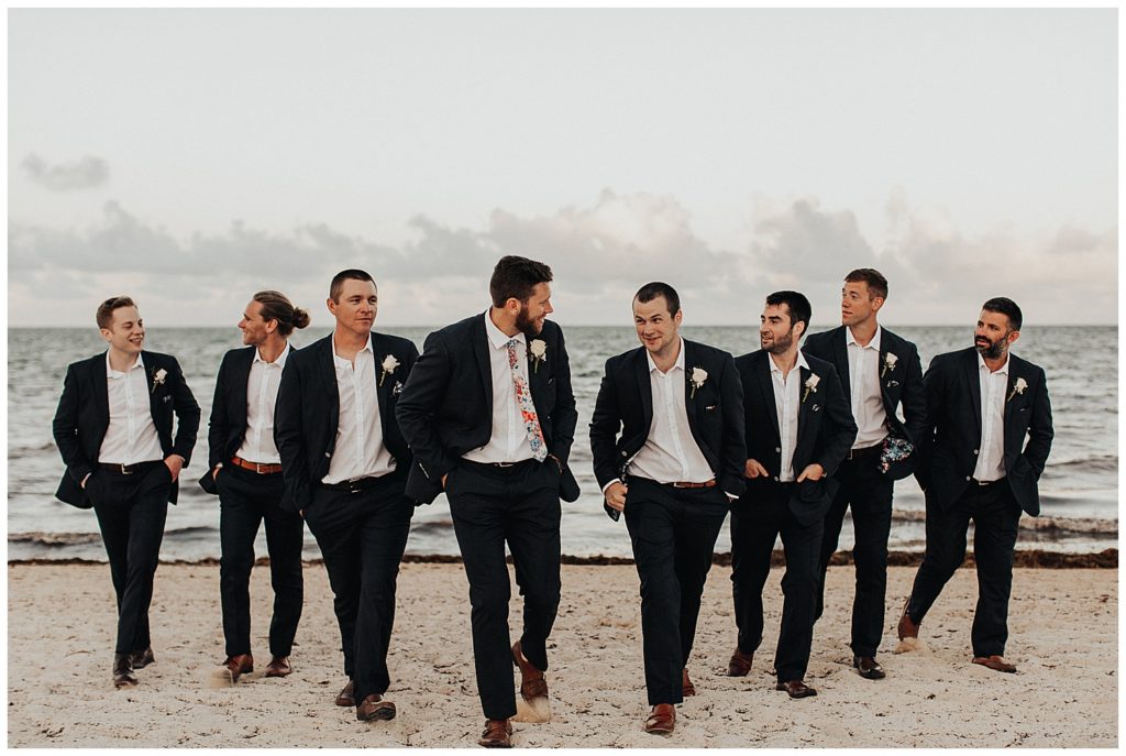 groom and groomsmen taking photos on the beach before wedding ceremony in cancun mexico