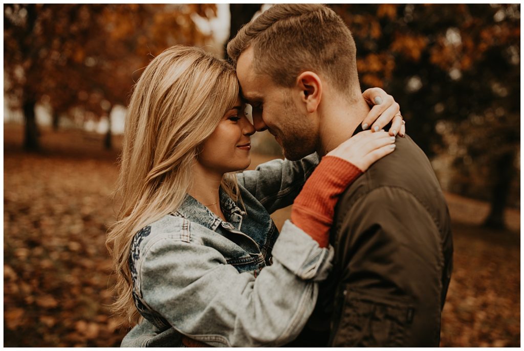 Engaged couple taking portraits in Kentucky, surrounded by fall leaves