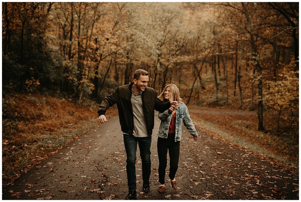 Engaged couple taking portraits in Kentucky, surrounded by fall leaves