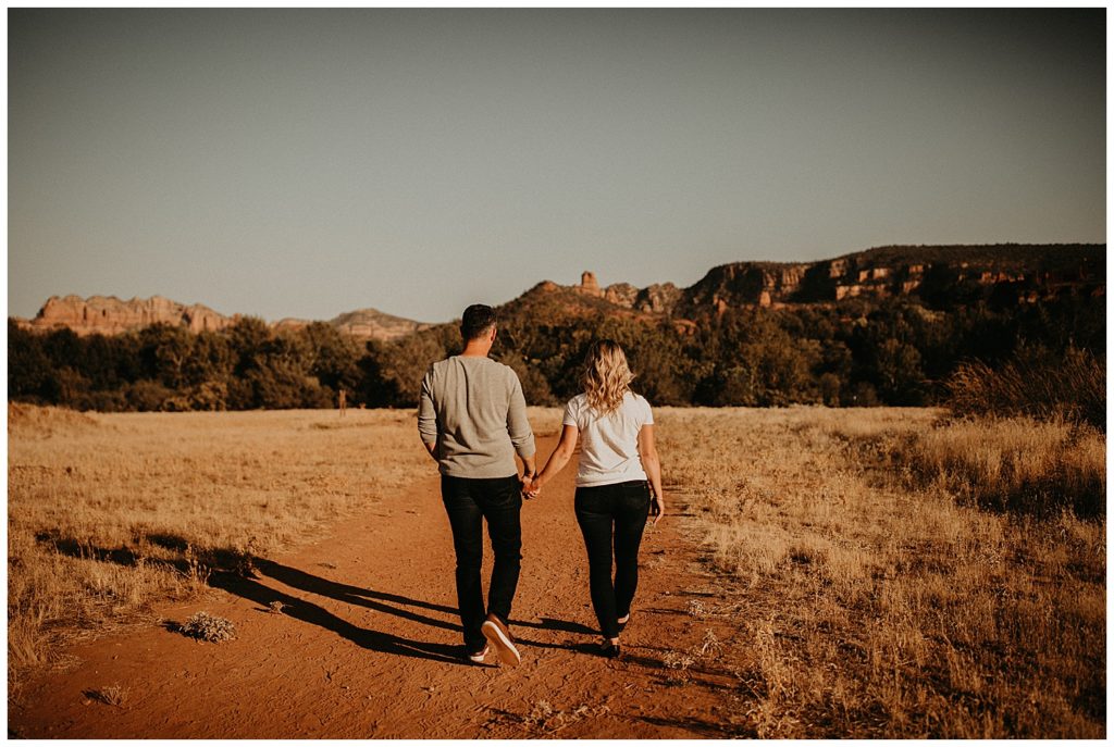 couple holding hands while taking engagement photos at cathedral rock